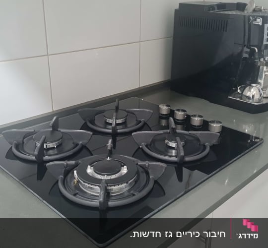 כיריים גז שחורות עם ארבעה מבערים על משטח מטבח